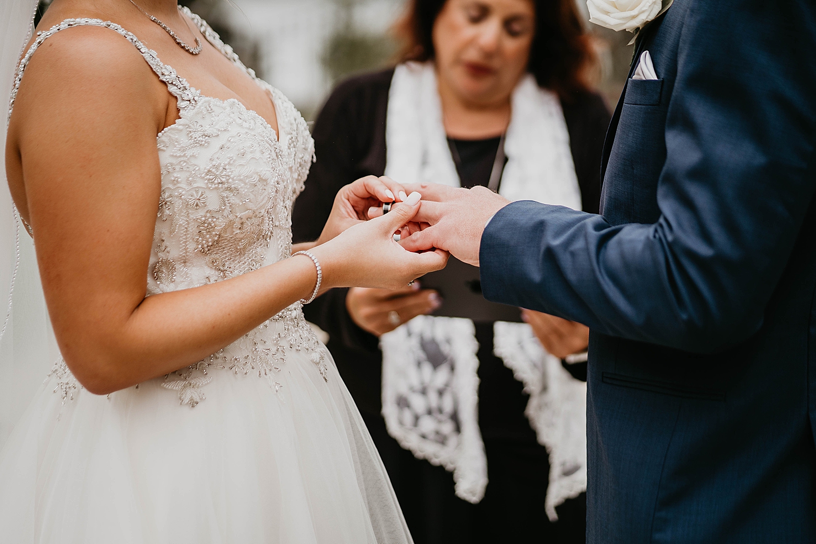 Bride putting ring on Groom's finger