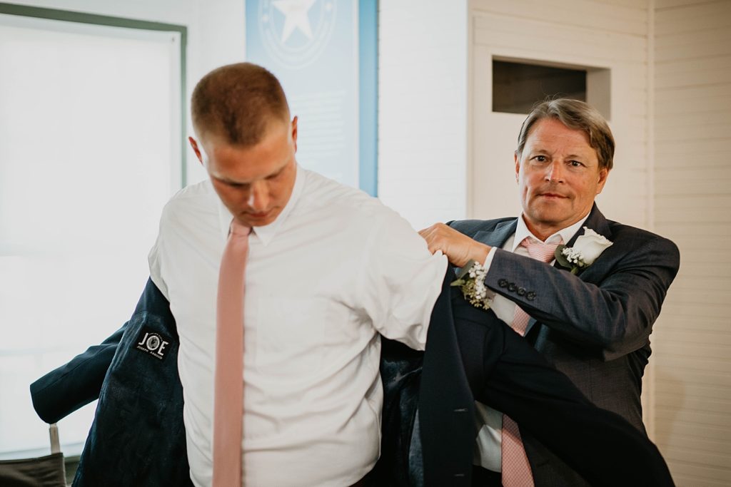 Groom getting help putting on jacket Getting Ready