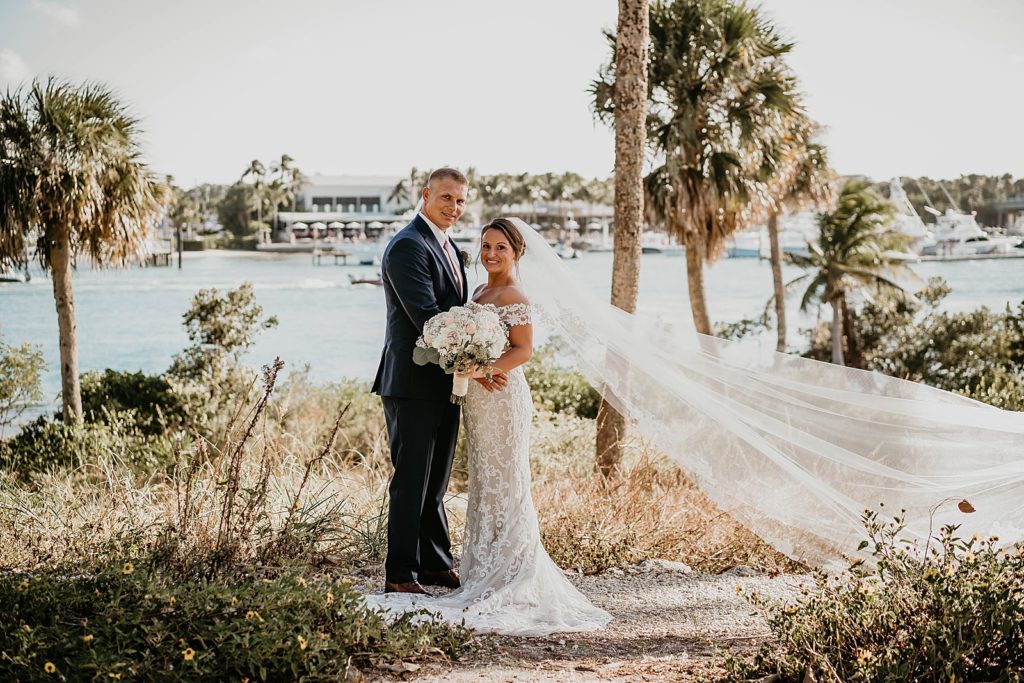 Bride and Groom holding each other in front of water with white bouquet